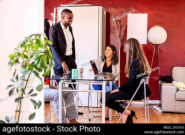 Smiling businessman discussing with colleagues in coworking office