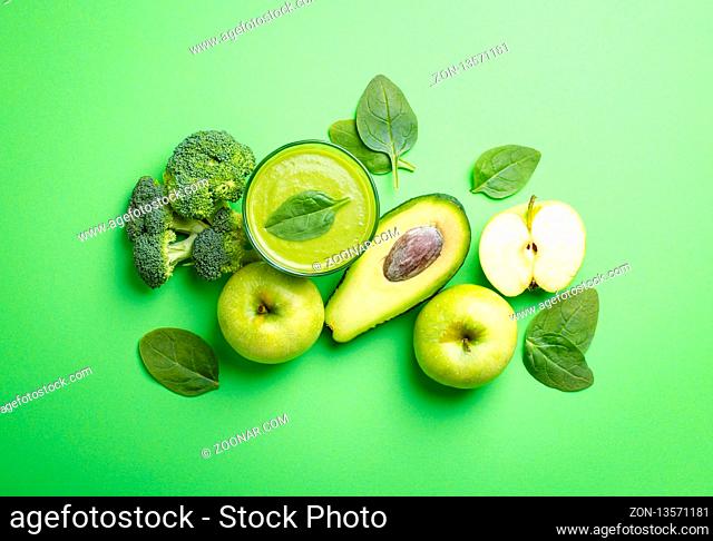 Ingredients for making green healthy smoothie with broccoli, apples, avocado, spinach on green pastel background. Clean eating, detox plan, diet