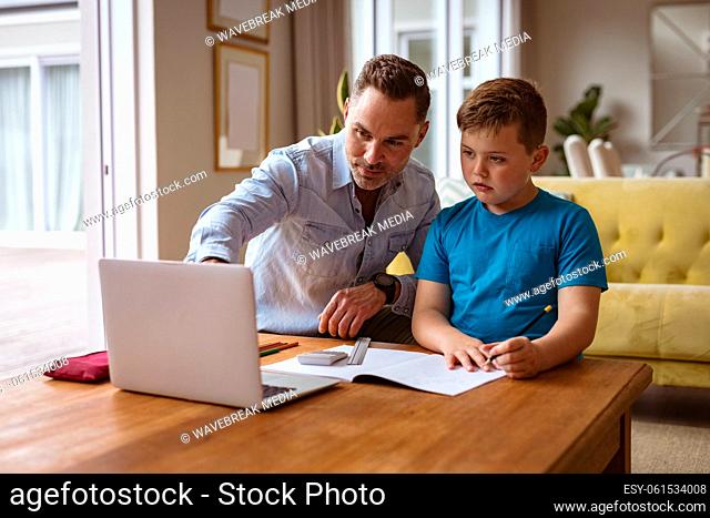 Caucasian father using laptop to help his son with homework at home