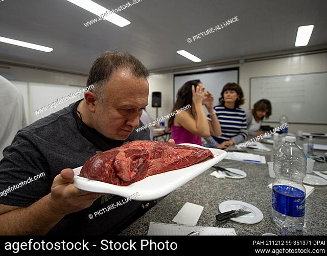 dpatop - 01 December 2021, Argentina, Buenos Aires: A course participant smells a piece of raw beef during a lesson in the new meat sommelier training course at...