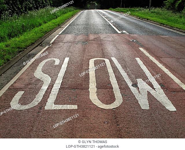 England, Warwickshire, Warwick. Slow warning sign written on the surface of a rural English road