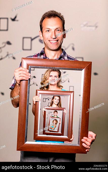 Happy father holding portrait with his family each is located inside their own frame