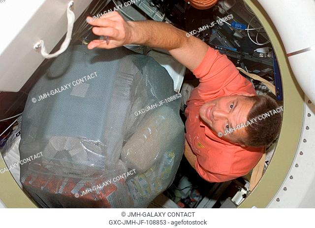 Astronaut Doug Wheelock, STS-120 mission specialist, moves a stowage bag through a hatch on Space Shuttle Discovery during flight day two activities