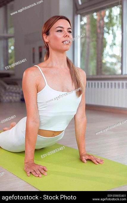 Young woman practicing yoga, doing ?obra exercise
