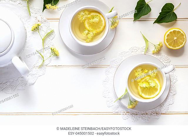 Two cups of herbal tea with linden flowers and lemon on a white table, with copy space