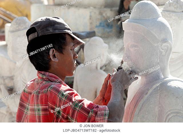 Myanmar, Mandalay, Mandalay. A stone carving workshop in Mandalay in Myanmar with man working on Buddha statue