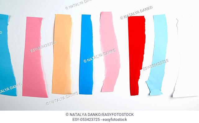 torn strips of colored paper on a white background, flat lay