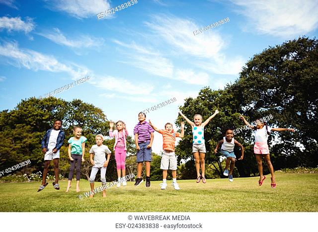 Smiling kids jumping together during a sunny day