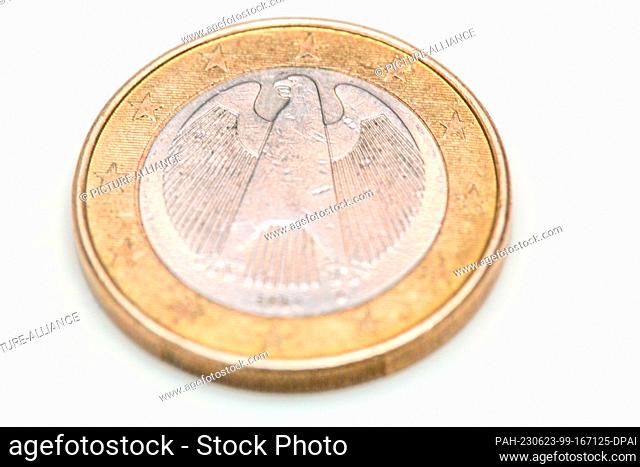 SYMBOL - 22 June 2023, Berlin: An old 1-euro coin lies on the table. It bears the traditional symbol of German sovereignty, the eagle