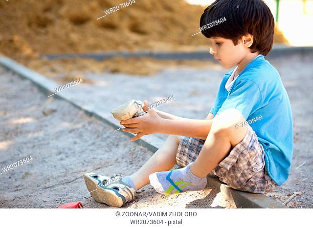 boy shakes the sand out of the shoe