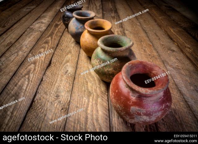 row os small grunge clay pots with rough color finish on a weathered wood, soft focus image shot with lensless pinhole camera