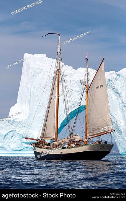 Ship sailing past iceberg on sunny Atlantic Ocean Greenland