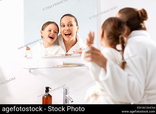 mother and daughter looking to mirror in bathroom