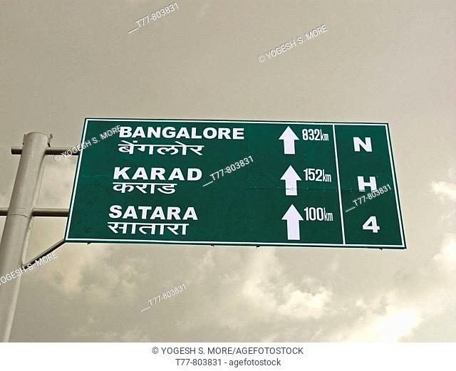 A signboard on a national highway four roadside is showing distances of Bangalore, Karad, Satara from Pune  Pune, Maharashtra, India