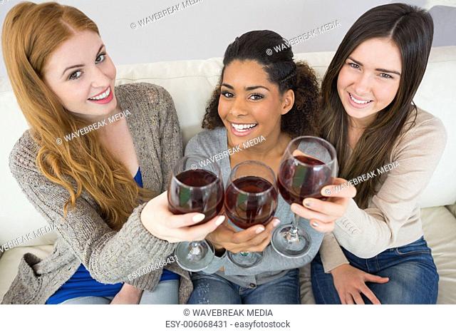 Cheerful young female friends toasting wine glasses