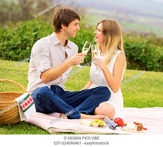 Attractive couple drinking champagne on romantic afternoon picnic in countryside