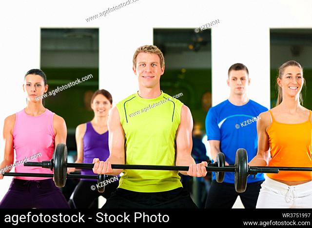 Group of five people exercising using barbells in gym or fitness club to gain strength and fitness
