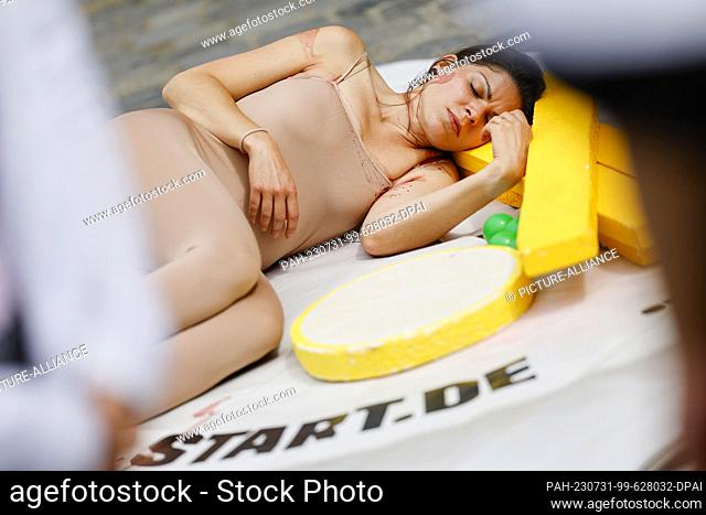 31 July 2023, Bavaria, Nuremberg: An activist lays herself as a ""bloody steak"" on an oversized plate in front of the Lorenzkirche