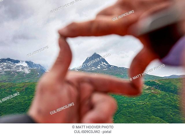 Senior man and son framing mountain peak with hands, close up, Valdez, Alaska, USA