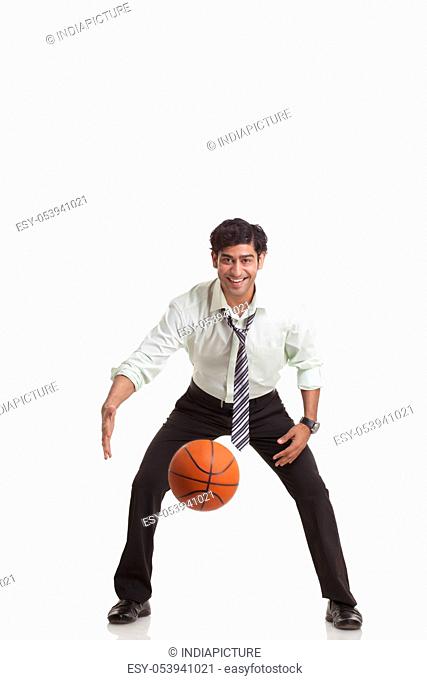 Portrait of young businessman playing basketball