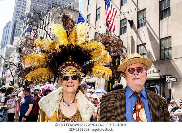 New York, NY - April 16, 2017. A couple at New York's annual Easter Bonnet Parade and Festival on Fifth Avenue. She is wearing an elaborate hat with yellow and...