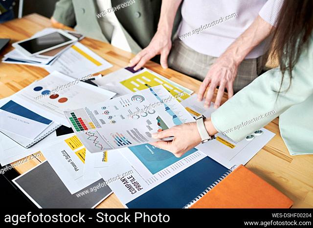 Office colleagues reviewing infographics on desk at office