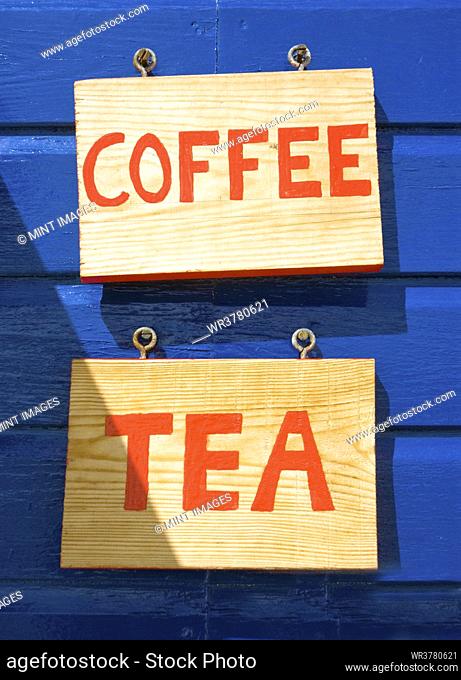 Coffee and tea signs on wooden wall or building exterior