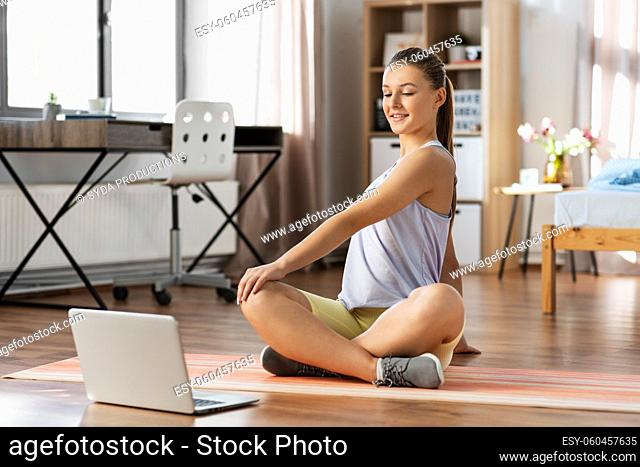 happy teenage girl with laptop exercising at home