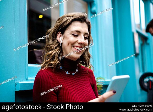 Happy woman using smart phone in front of window