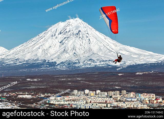 PETROPAVLOVSK-KAMCHATSKY, KAMCHATKA, RUSSIA - NOVEMBER 21, 2014: Paraglider flying over Petropavlovsk-Kamchatsky City on the background of the active Koriaksky...