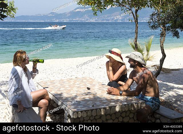 Three persons sitting at a table on the Beach in Zhanpovel Bay, Peninsula of Karaburun, within the Karaburun-Sazan Marine Parc, Vlore bay, Albania