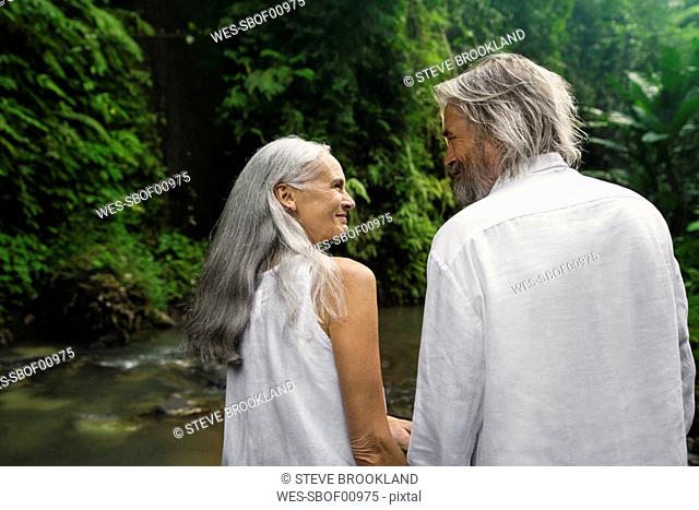 Handsome senior couple smiling at each other in tropical jungle