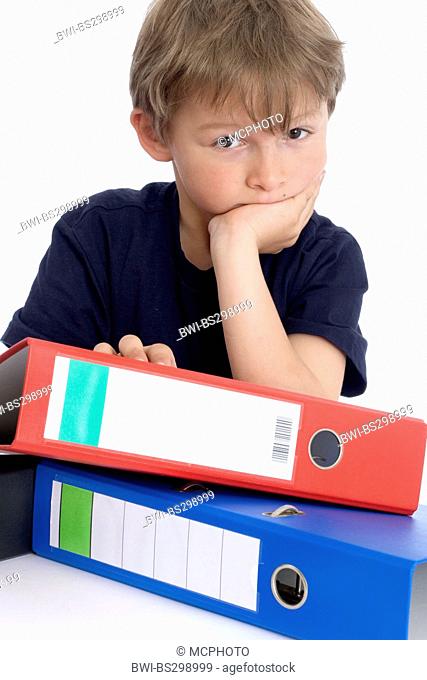 little boy leaning on a stack of files with a smile