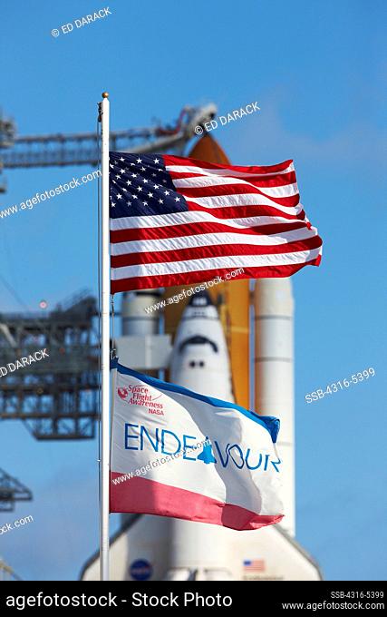 American flag and Space Shuttle Endeavour Flag in foreground frame the cockpit of Space Shuttle Endeavour ready to launch on STS-130 at Pad 39A