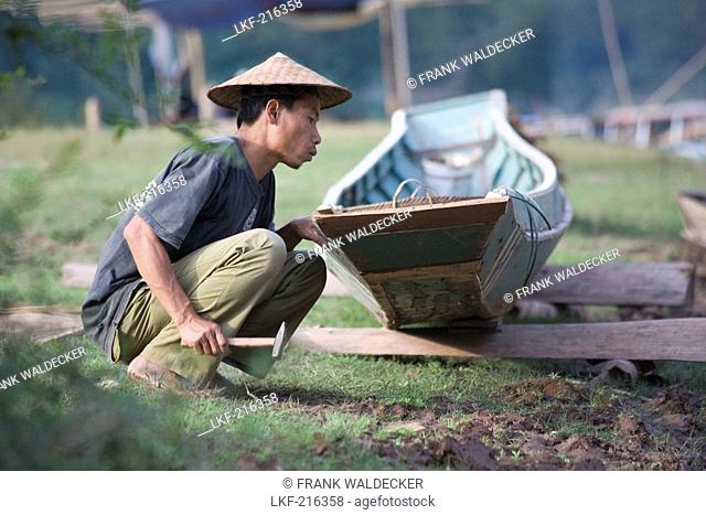 Fisherman repairing his boat at the fishing village Muang Ngoi Kao, Luang Prabang Province, Laos