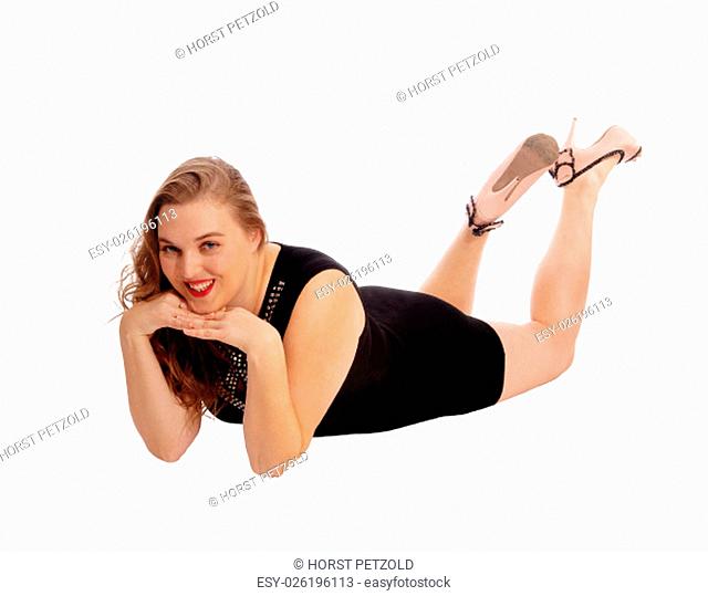 A pretty woman in a black dress lying on the floor with her hands under.her chin, isolated for white background.