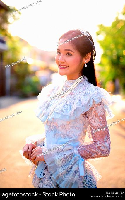 Portrait of young beautiful Asian woman wearing Thai traditional clothes outdoors