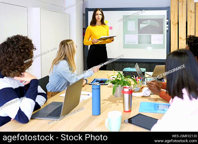 Female professional discussing over projection screen in meeting at office