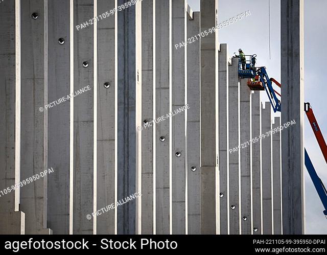 04 November 2022, Schleswig-Holstein, Neumünster: Two workers in cherry pickers during assembly work on the supporting structure of a logistics hall
