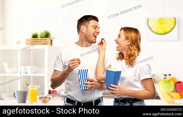 happy couple in white t-shirts eating popcorn