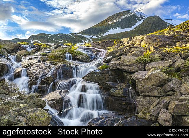 Waterfall with mountains in background with snow on them, evening light with nice colored sky, Gällivare county, Stora sjöfallet nationalpark, Swedish Lapland