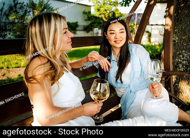 Women sitting on porch swing enjoying wine