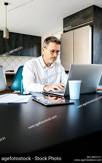 Businessman working on laptop at domestic kitchen in home office