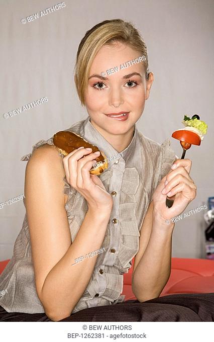 Woman eating vegetables and eclair