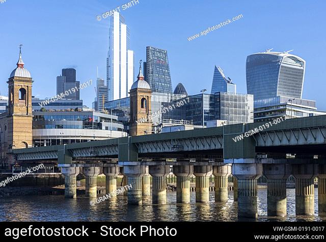 View to the City looking north east from Southwark on a bright blue sky day. Cannon Street railway bridge cuts the frame