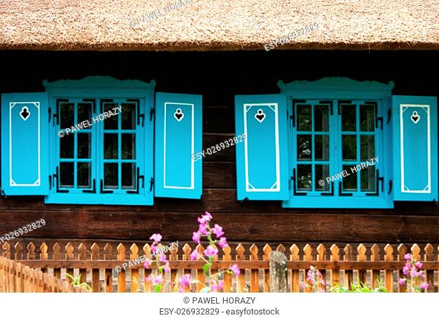 historic wooden house with blue shutters and a thatched roof