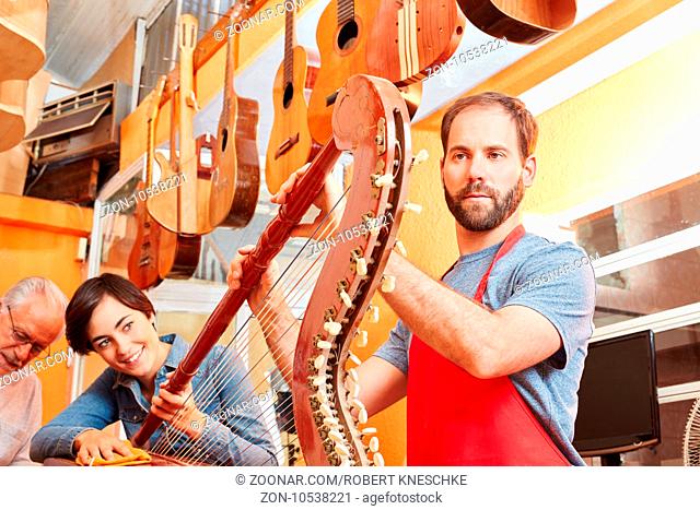 Gitarrenbauer als Experte bei der Pflege einer Harfe in der Werkstatt