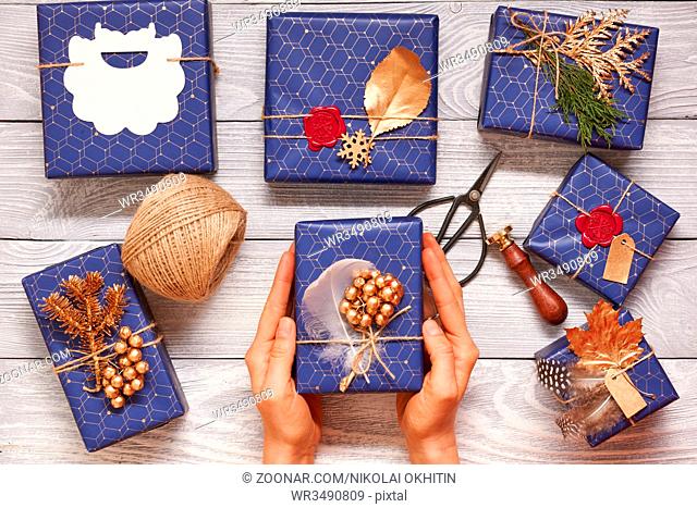 Woman wrapping christmas gifts. Creatively wrapped and decorated christmas presents in boxes on wooden background.Top view from above