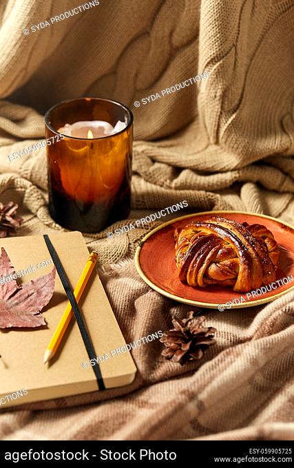 diary, pencil, cinnamon bun and candle in autumn