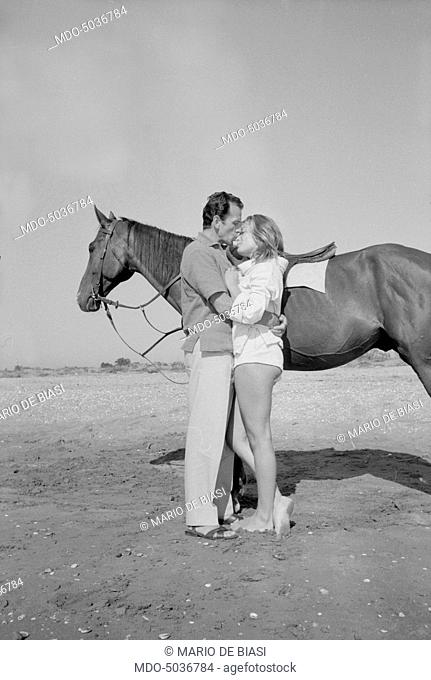 Italian actor Massimo Girotti kissing British actress Belinda Lee after a horse ride on the beach during the XVIII Venice International Film Festival